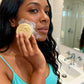 Woman applying soap to her face in a bathroom.